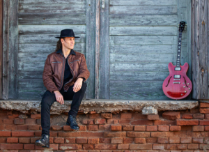 Peter Kern auf einem Presse-Foto mit roter Gitarre