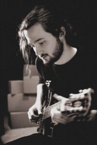 Michael J. Keplinger auf einem schwarz-weiß Pressefoto mit Gitarre
